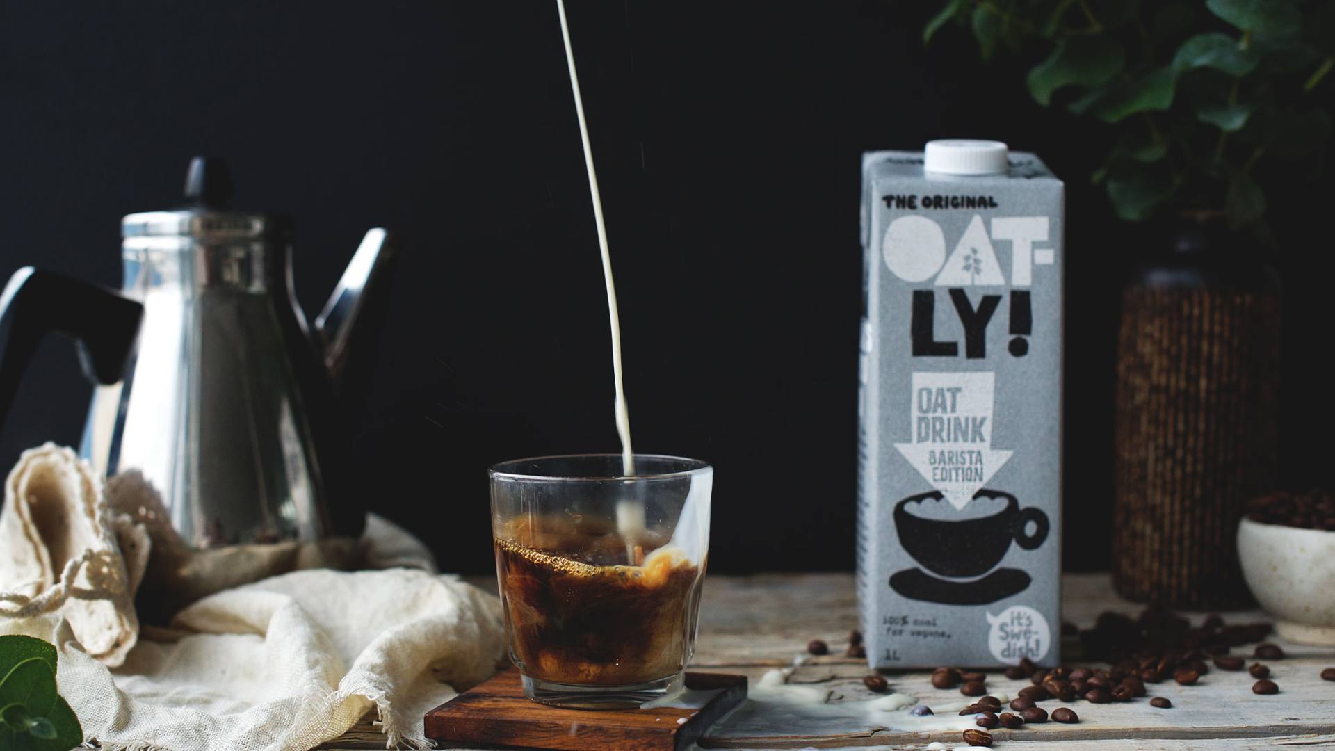 Oatly being poured into a coffee cup.